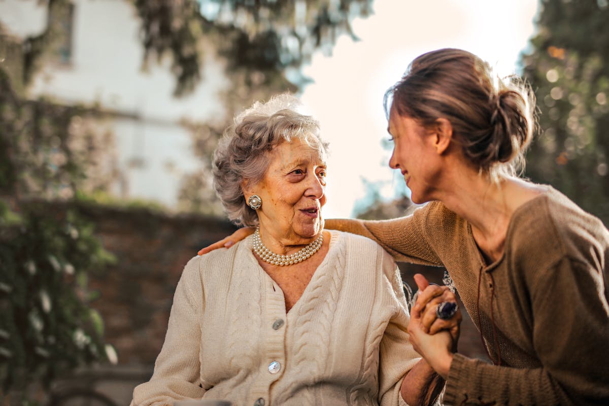 Caregiver sharing a warm moment with an elderly woman outdoors