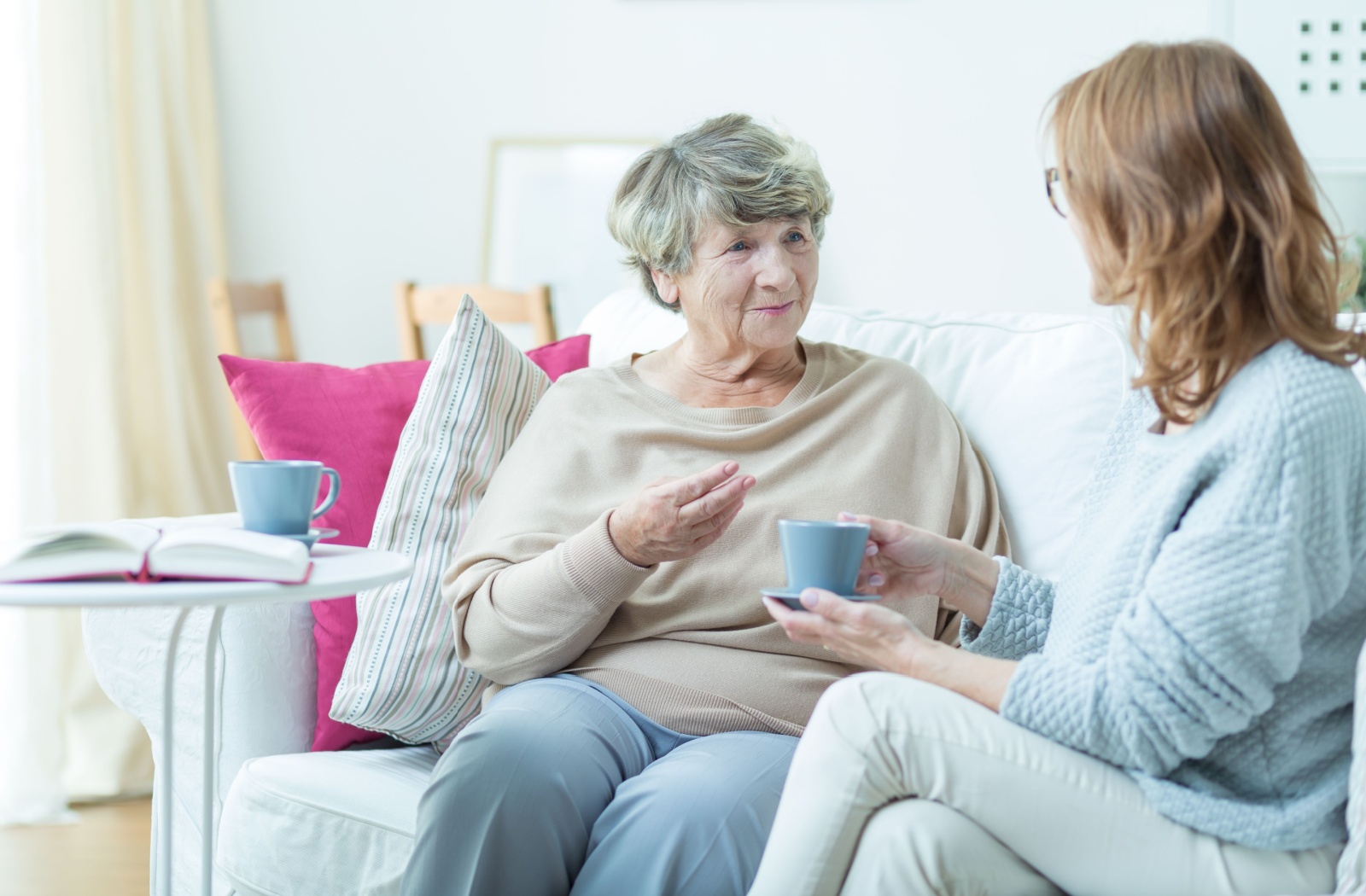 Caregiver and senior woman sharing a warm conversation over tea